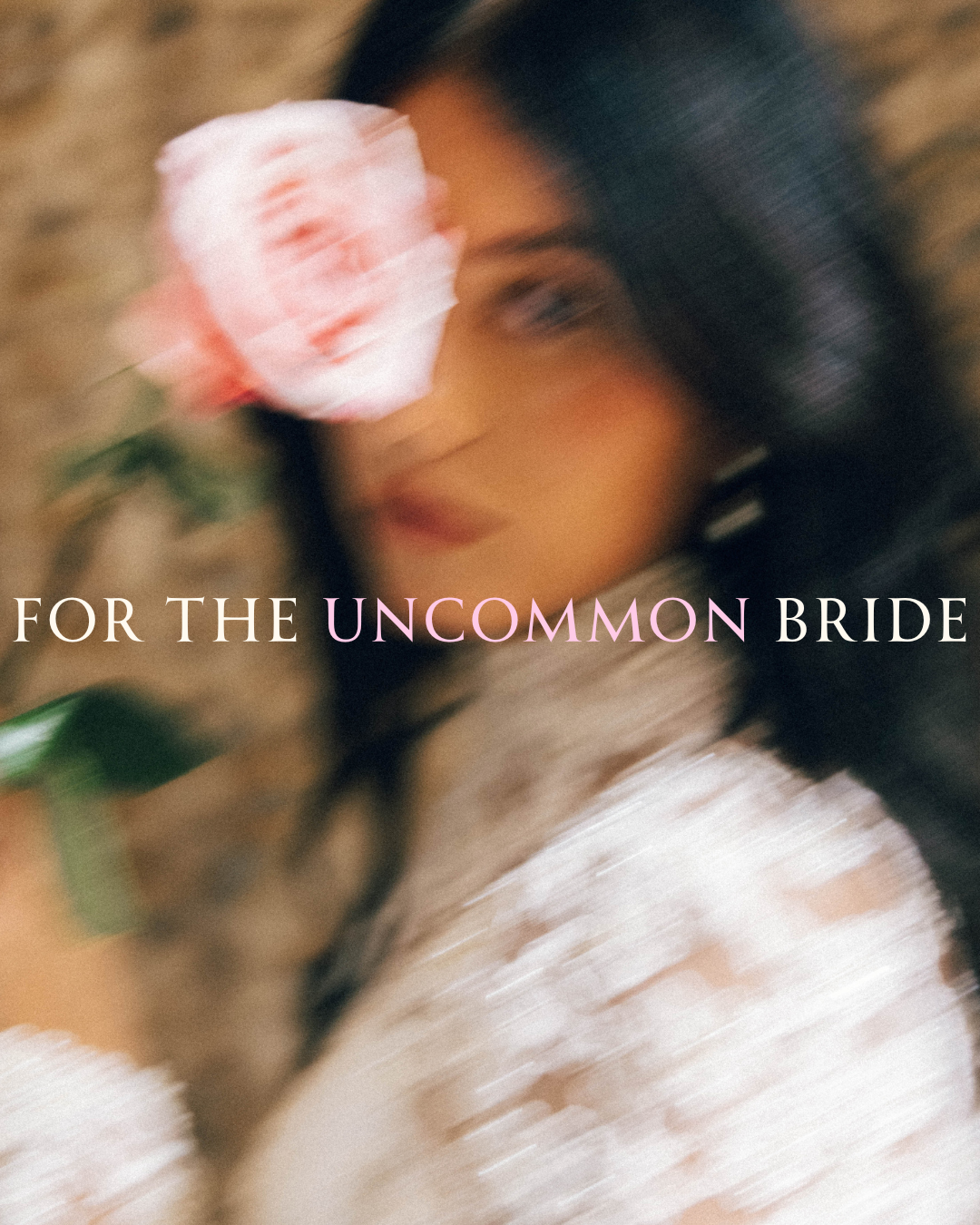 A motion-blurred portrait of a bride in high-collared lace holding a pink rose across her face