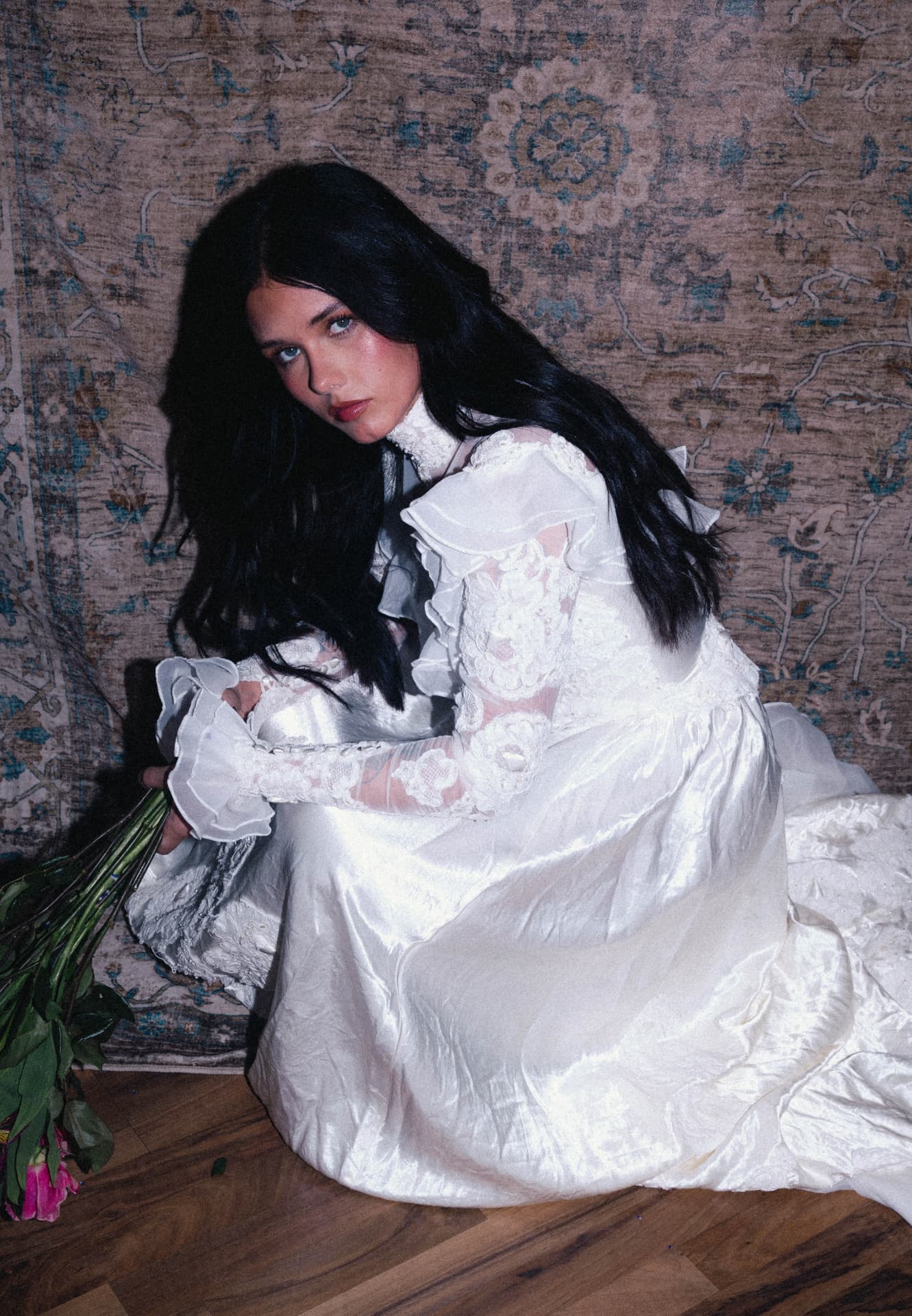 A bride crouching with a bunch of roses