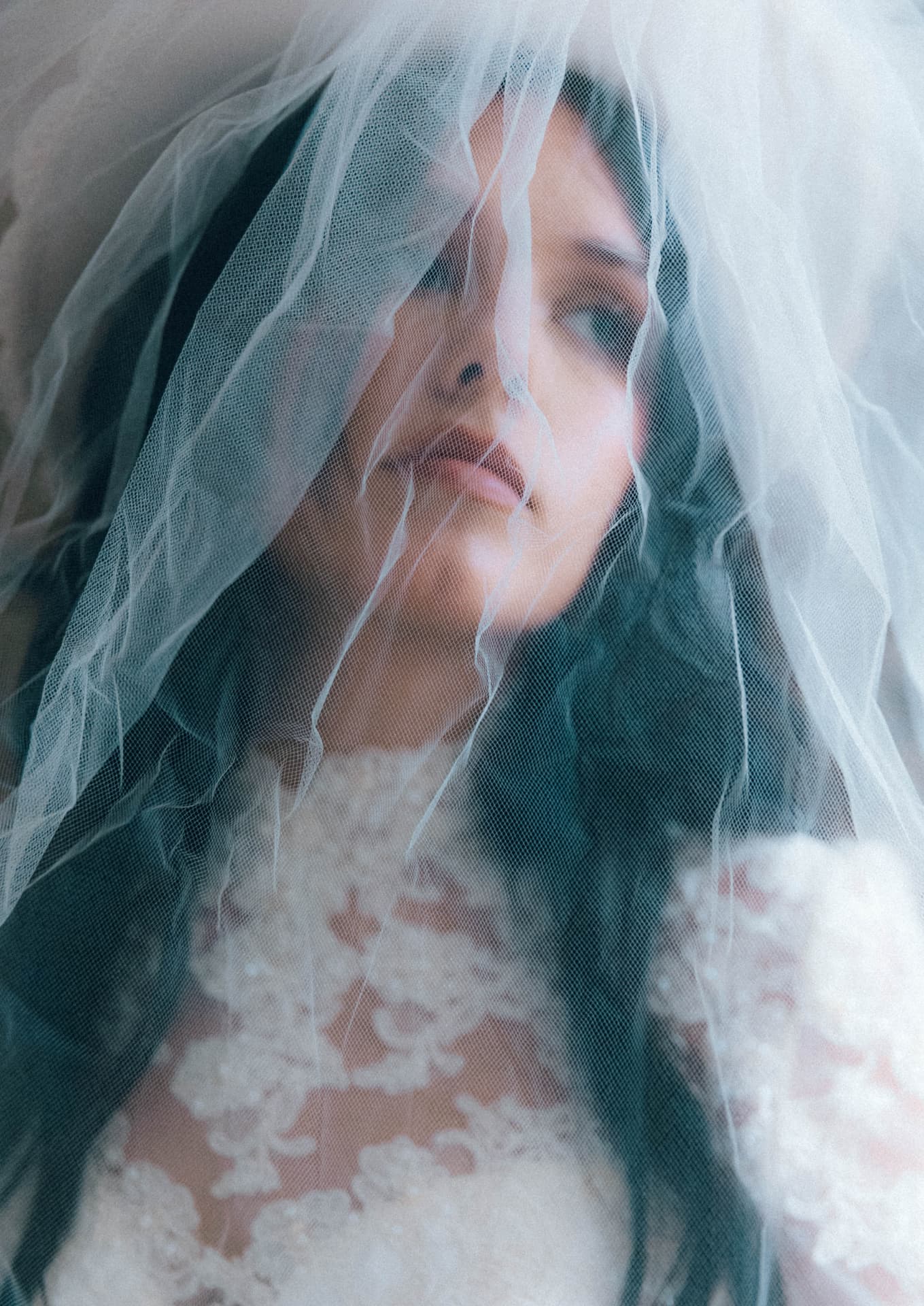 A bride looking up beneath a draped veil